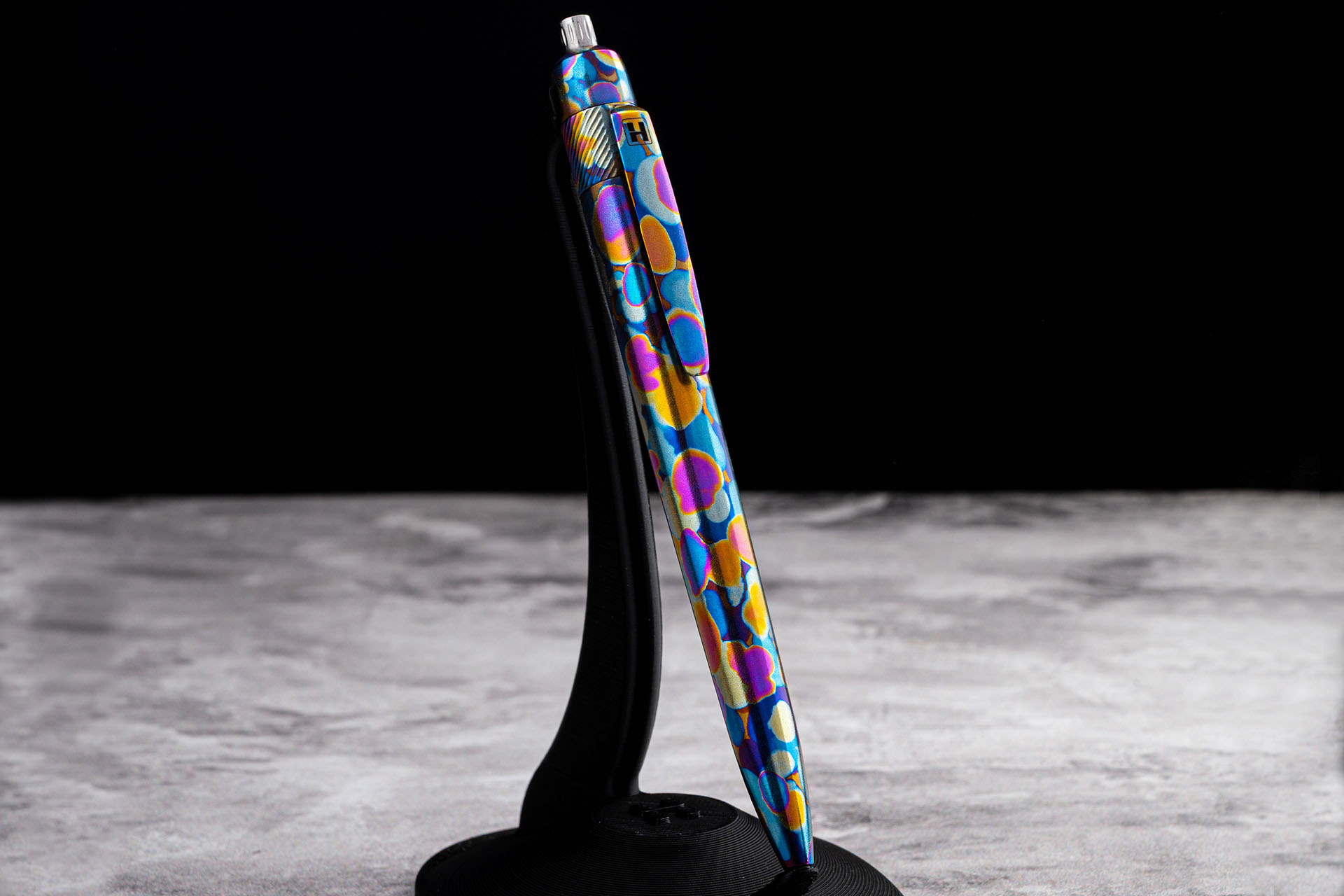 Herman Epika artistic anodized titanium EDC pen standing on display stand