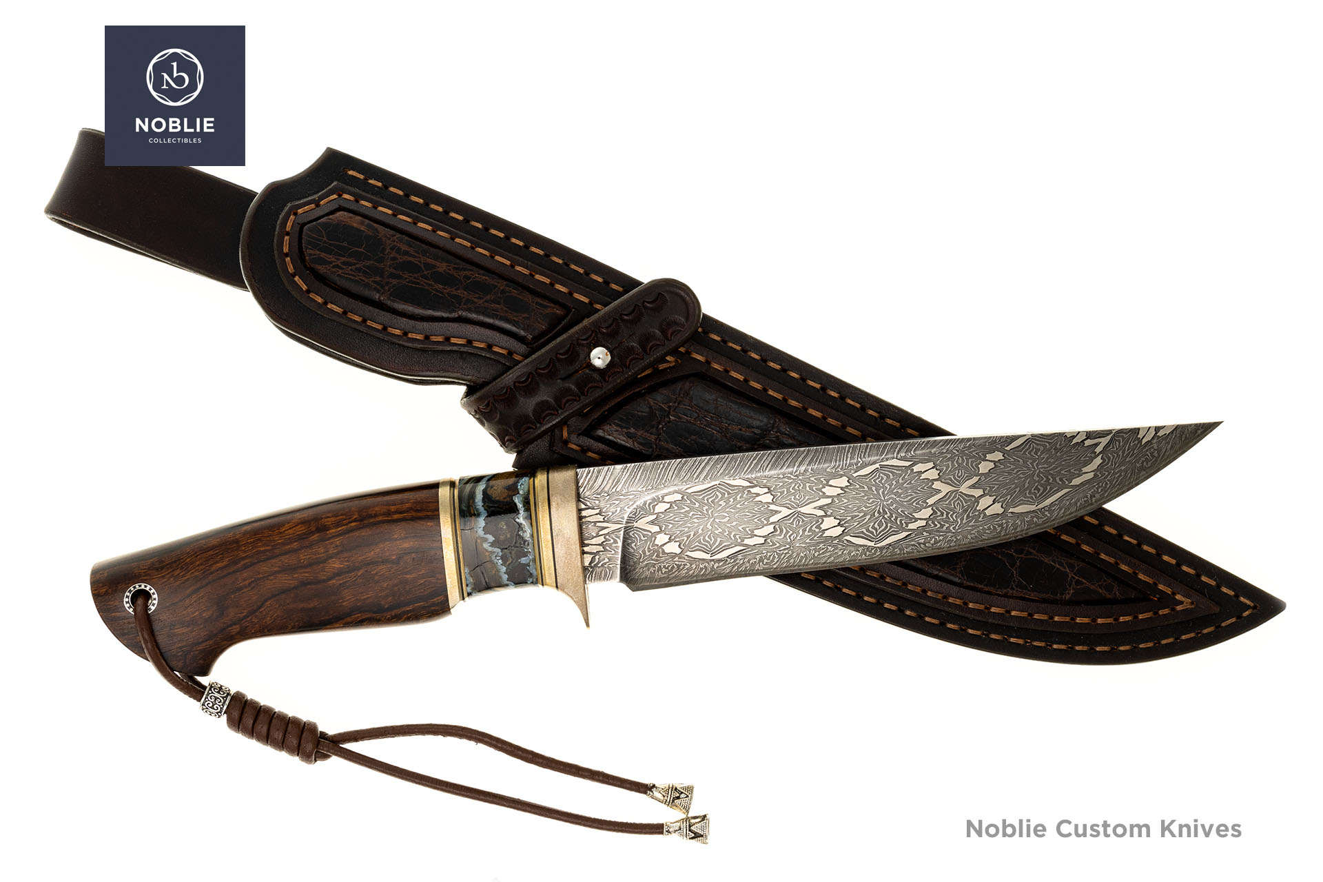 Mosaic Damascus knife resting across its dark leather sheath with textured panels and contrasting stitching
