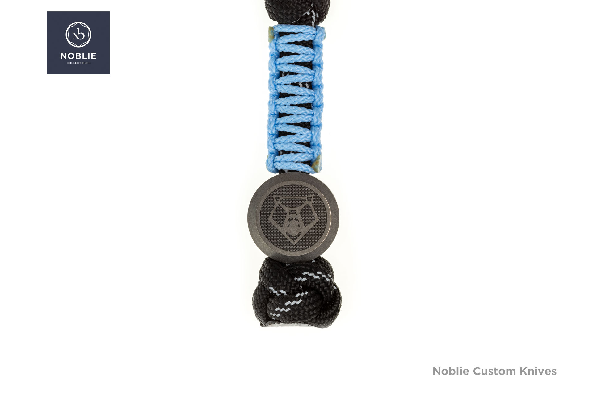 Shirogorov Pivot titanium bead with a bear-head emblem on a blue-and-black paracord lanyard